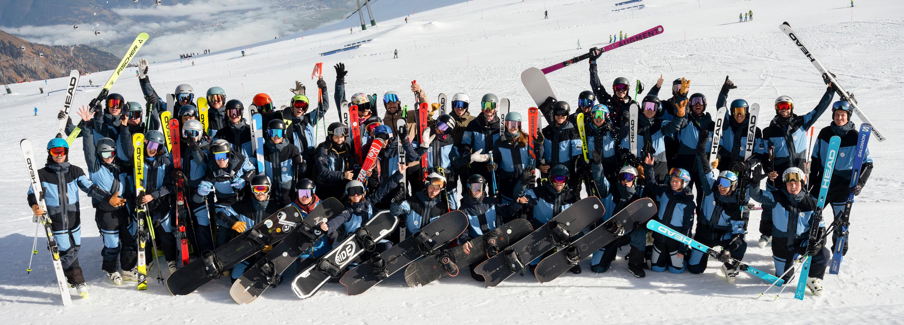 Gruppenfoto von Schifahrer*innen und Snowbordfahrer*innen auf der Piste